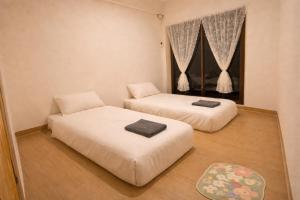 two beds in a small room with a window at The Layover Donmueang Airport Hostel in Thung Si Kan