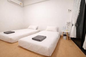 two beds in a room with white walls at The Layover Donmueang Airport Hostel in Thung Si Kan