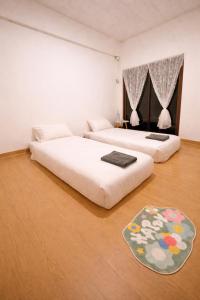 a bedroom with two beds and a rug on the floor at The Layover Donmueang Airport Hostel in Thung Si Kan +7 photos