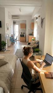 a woman sitting at a table with a laptop in a living room at Maria's Studio No3 in Heraklion in Thérissos