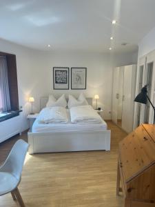 a white bedroom with a white bed and a chair at Altstadtappartment Plötze 13 Limburg in Limburg an der Lahn
