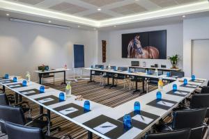 a conference room with tables and chairs and a screen at Renaissance Paris Hippodrome de St. Cloud Hotel in Rueil-Malmaison +62 photos