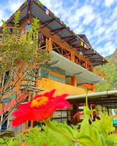 a building with a red flower in front of it at Mazel Tov Stays, Tirthan Valley in Gushaini