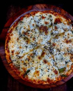 a cheese pizza sitting on top of a wooden table at Mazel Tov Stays, Tirthan Valley in Gushaini