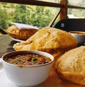 a table with a bowl of soup and some bread at Mazel Tov Stays, Tirthan Valley in Gushaini +26 photos
