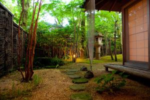 a garden with a bench and a path at Ryotei Tanokura in Yufu