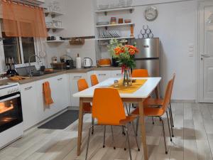 a kitchen with a white table and orange chairs at Aura in Gerakini