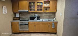 a kitchen with wooden cabinets and a sink at Levente vendégház in Szilvásvárad