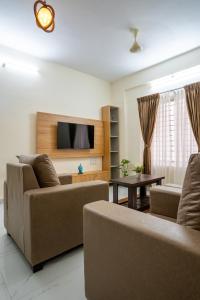 a living room with two couches and a flat screen tv at Odilia Apartelle in Bangalore