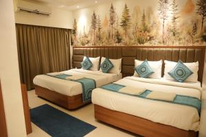 a bedroom with two beds and a painting on the wall at Hotel Sai Seeta Palace Newly Renovated in Shirdi