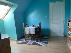 a dining room with a table and chairs and a blue wall at La Suite Dorée à Amaryllis in La Guierche