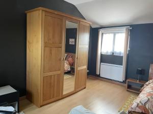 a large wooden cabinet in a bedroom with a window at La Suite Dorée à Amaryllis in La Guierche