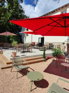 a patio with tables and chairs and red umbrellas at Un grain d'folie in Villié-Morgon +19 photos