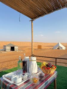 a table with a tray of food and a bowl of fruit at Night Stars Camp in Badīyah