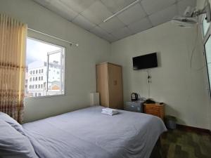 a bedroom with a white bed and a window at Guesthouse Big Lucky in Da Lat