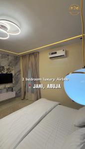 a bedroom with a white bed and a television at AA Luxury Apartments in Abuja