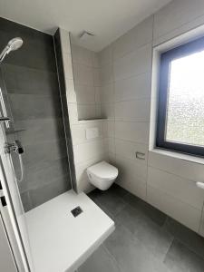 a white bathroom with a toilet and a shower at Hotel Rammelkamp in Nordhorn