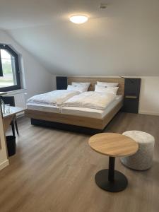 a bedroom with a bed and a table and a stool at Hotel Rammelkamp in Nordhorn