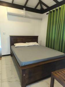 a bed in a room with a green curtain at Rainforest Mount Villa in Nelluwa +29 photos