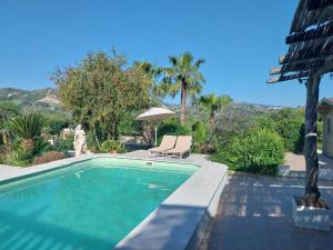 a swimming pool with a chair and an umbrella at Casa Papaver Relax Appartement in Coín
