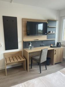 a room with a desk with a tv and a chair at Hotel Rammelkamp in Nordhorn