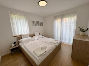 a bedroom with a large bed with white sheets at Vinopool Suites Badacsony in Badacsonytomaj