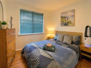 a bedroom with a bed with a dresser and a window at Humble & Homely in Rockingham