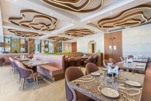 a dining room with tables and chairs and a ceiling with a painting at Hotel Altura CHHATRAL in Nandāsan