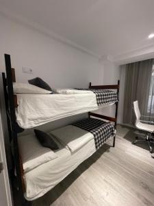 two bunk beds in a room with a chair at Igidelux 2 in Villajoyosa