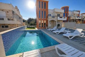 a swimming pool with white lounge chairs and a building at Villa Alera in Dobra Voda