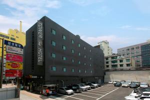 a large black building with cars parked in a parking lot at Towerhill Hotel in Busan