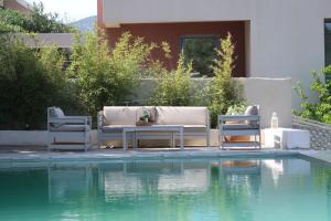 two chairs and a table next to a swimming pool at Hippie Bay Complex in Porto Rafti