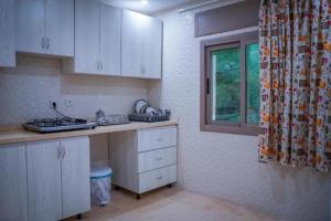 a kitchen with white cabinets and a sink and a window at hotel el amri akchour in Akchour