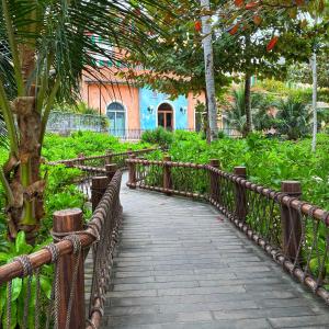 a wooden walkway in a park with trees and plants at Leto Hotel Central Sunset Town in Phú Quốc