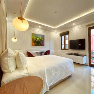 a bedroom with a bed and a table and a tv at Leto Hotel Central Sunset Town in Phú Quốc