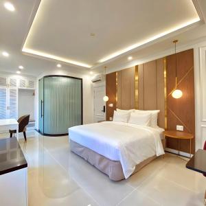 a bedroom with a large white bed and a desk at Leto Hotel Central Sunset Town in Phú Quốc