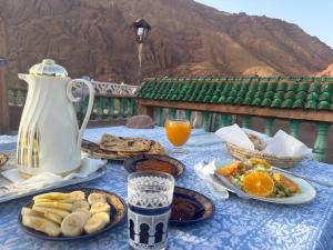 a table with plates of food and a pitcher of orange juice at Red Rocks Guest House in Tamellalt