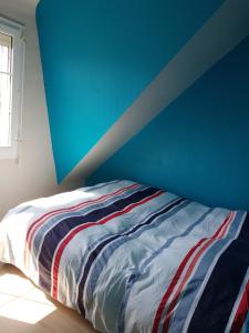 a bed in a room with a blue wall at Maison de Crozon in Crozon