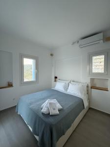 a white bedroom with a bed with a towel on it at Villa Manesi in Kithnos