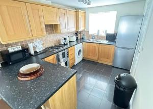 a kitchen with wooden cabinets and a black counter top at Gem Relax in Leighton Buzzard