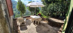 a table and chairs with an umbrella on a patio at La Benabbiana in Bagni di Lucca