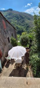 a white umbrella and chairs in front of a building at La Benabbiana in Bagni di Lucca +1 photo