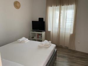 a white bedroom with a bed and a tv at Klancic 10 in Novi Vinodolski