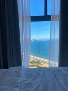 a bedroom window with a view of the ocean at The Seafront Condotel - Apec Mandala in Mui Ne