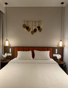 a bedroom with a large bed with two lights on the wall at The Seafront Condotel - Apec Mandala in Mui Ne