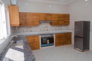 a kitchen with wooden cabinets and a black refrigerator at Tanga New Apartments in Tanga