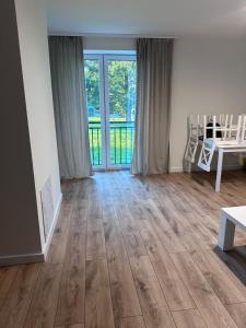 a living room with wooden floors and a sliding glass door at Apartament Ełcka 2- Mazury in Orzysz +1 photo