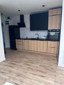a kitchen with wooden cabinets and a tile floor at Apartament Ełcka 2- Mazury in Orzysz