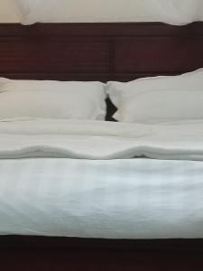 an unmade bed with white sheets and pillows at BRACCK Suites in Nakwero