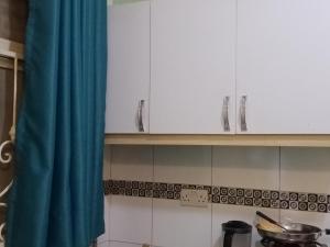 a kitchen with white cabinets and a blue curtain at BRACCK Suites in Nakwero